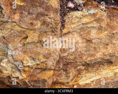 Close-up of layered sedimentary rock with cracks, textures, and earthy mineral tones. Stock Photo