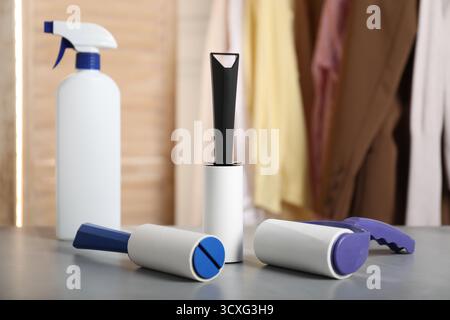 Lint rollers and bottle of cleaning product on grey table indoors, closeup Stock Photo