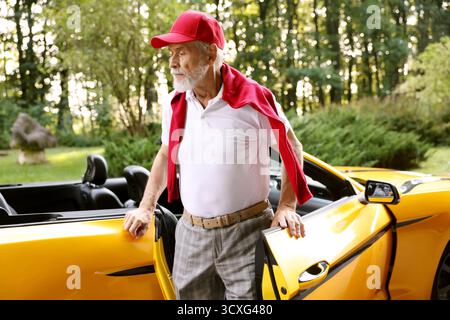 Stylish senior man getting out of modern cabriolet outdoors Stock Photo