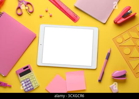 Set of school stationery with tablet computer on yellow background Stock Photo