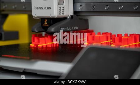 Jurmala, Latvia - 14.10.2025: Close-up 3D printer Bambu Lab A1 with AMS. 3D printer creating vibrant red objects in a modern workspace with advanced Stock Photo