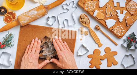 Christmas gingerbread different shaped with ingredients for gingerbread and the hands of a woman baker, top view, flat lay Stock Photo