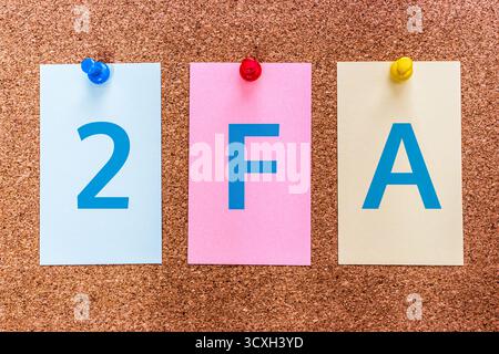 Conceptual 3 letters keyword 2FA (two-factor authentication) on multicolored stickers attached to a cork board. Stock Photo