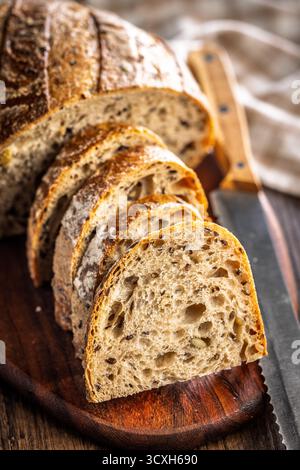 Photo of sliced ​​baked sourdough bread on cutting board on a wooden table. Stock Photo