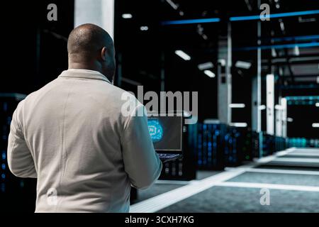 Close up of data center engineer using artificial intelligence on laptop to troubleshoot connectivity issues. Server room worker working with AI machine learning, auditing systems for vulnerabilities Stock Photo