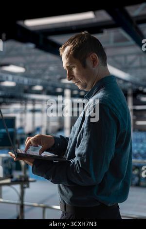 Admin on data center industrial platform analyzing infrastructure performance, monitoring potential failures. Server farm employee doing job tasks, debugging software issues Stock Photo