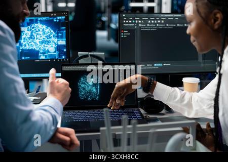 Lead programmer and female engineer in data center updating AI automation scripts. Server room IT expert and african american woman programming artificial intelligence algorithms at desk Stock Photo