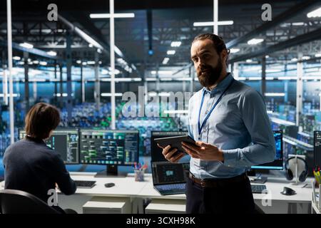 Businessman in data center presents machine learning tech to shareholders, demonstrating capabilities. IT professional briefing investors on server hub artificial intelligence hardware rigs Stock Photo