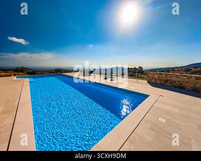 Infinity Pool Overlooking the Mediterranean Sea and Hills at Sunset – Luxury Villa View in Vibrant Evening Light Stock Photo