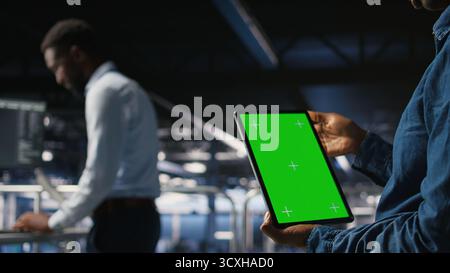 Data center engineers monitoring neural network LLM visualization using green screen tablet. Server farm IT experts oversee rigs powering machine learning processes using chroma key device, Stock Photo