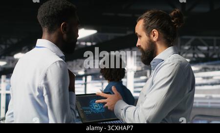 Server farm coworkers doing infrastructure AI machine learning automatization. Data center computer scientists collaborating to maintain servers using artificial intelligence Stock Photo