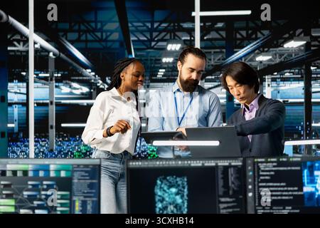 Team of engineers in data center monitoring AI applications, adjusting machine learning. Server hub workers performing load balancing, enhancing artificial intelligence software performance Stock Photo