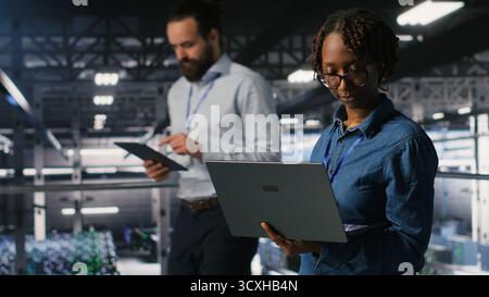 Data center teamworking colleagues running diagnostics on equipment to identify errors, doing brainstorming. Engineering team preventing rigs failure to minimize downtime Stock Photo