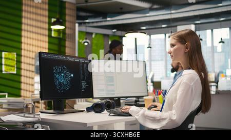 Female technician testing generative AI machine learning algorithms at work. IT professional scaling productivity with artificial intelligence large language model written code, camera A Stock Photo