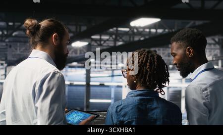 Software developers in data center monitoring AI LLM visualization. Server farm teamworking colleagues doing brainstorming, overseeing rigs powering machine learning processes Stock Photo