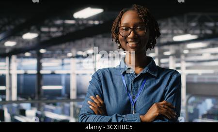 Happy technician next to server hub engineering team colleagues reviews AI diagnostics. Cheerful african american woman working in data center to maintain operational reliability Stock Photo