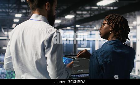 Data center system administrators performing maintenance on supercomputers used for AI. Engineering team managing server hub rigs used for deep learning training Stock Photo