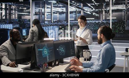 Data center team of technicians working on neural network software development. Server hub colleagues implementing deep learning artificial intelligence technology in workplace, camera A Stock Photo