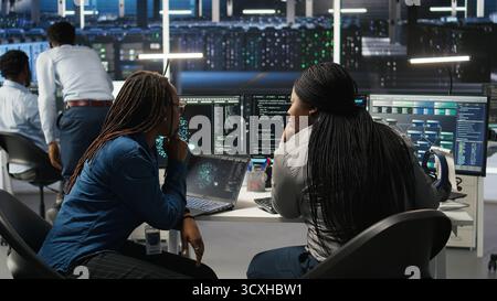 Data center coworkers doing brainstorming, using artificial intelligence machine learning models to configure equipment. IT experts cooperating in server farm, working on optimizing systems, camera A Stock Photo