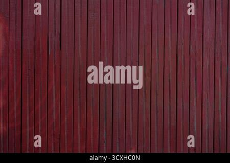 Dark red wooden wall with vertical planks, subtle natural texture, showcasing weathered wood surface in moody trendy color of year. Concept of wood Stock Photo