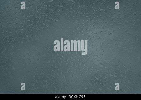 Raindrops on a grey surface creating a textured and moody abstract pattern. Stock Photo