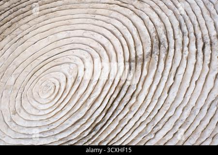 Close-up of concentric circular texture in light stone surface, showing natural pattern, depth, and organic design ideal for abstract backgrounds Stock Photo