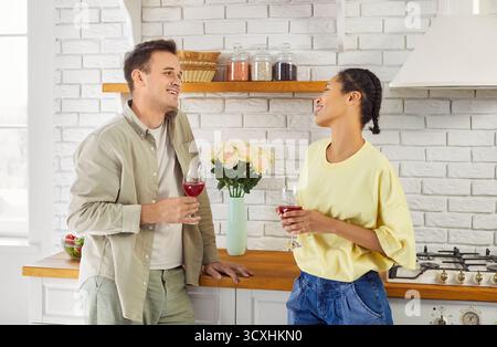 Happy conversation of smiling couple holding glasses of red wine at home together Stock Photo