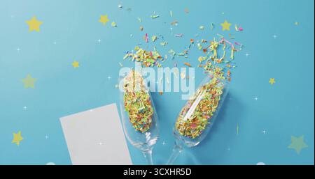 Confetti and stars image over champagne glasses on blue background Stock Photo