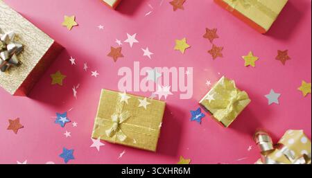 Gift boxes with ribbons over star confetti image on pink background Stock Photo