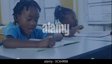 Writing school girl in blue T-shirt using pencil at desk in classroom, notebooks pencils copy space Stock Photo