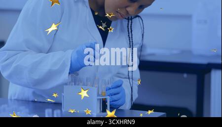 Female scientist in lab coat and gloves handling test tubes and pipette in lab, with rack Stock Photo