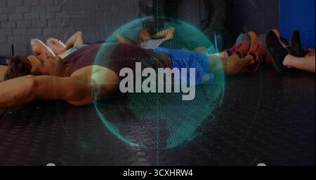 Projecting holographic globe hovering above six exercisers resting on gym floor with earphones Stock Photo
