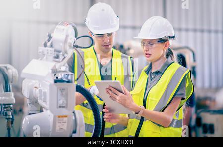 Engineers team mechanic using computer controller Robotic arm for welding steel in steel factory workshop. Industry robot programming software for aut Stock Photo