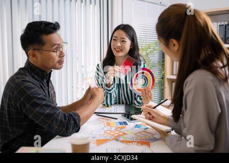 A group of UX/UI designers brainstorming creative ideas together, discussing color palettes and layout concepts for a new mobile application interface Stock Photo