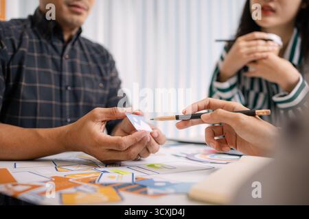 A group of UX/UI designers brainstorming creative ideas together, discussing color palettes and layout concepts for a new mobile application interface Stock Photo