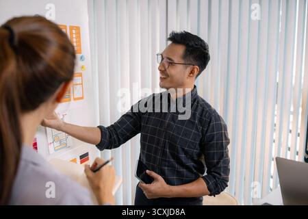 UX/UI designers collaborating during a creative workshop to test interface ideas and exchange feedback for app development, emphasizing teamwork and i Stock Photo