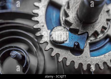 Macro view of watch mechanism showing gear, cam, and tightly coiled spring, highlighting intricate design. Stock Photo