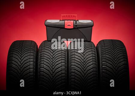 Car tires, new tyres, winter wheels, toolbox with instruments on red background. Stock Photo