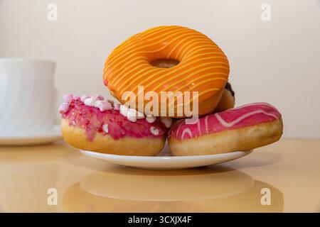 Colorful donuts with pink chocolate and marshmallow glaze on beige background Stock Photo