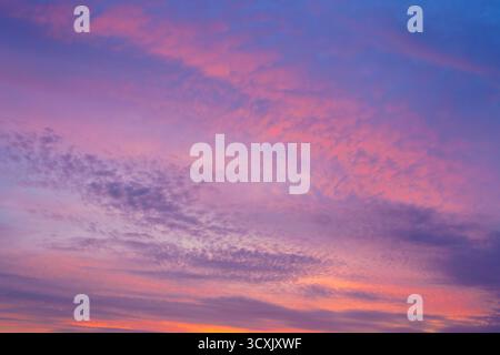 A beautiful sunset or sunrise sky with vibrant clouds changing from purple to orange is perfect for an abstract or nature background. Stock Photo