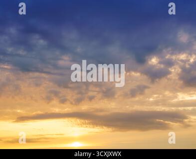Beautiful, colorful fluffy clouds in the evening or morning sky. Blue and yellow cloudscape at sunset or sunrise. A natural backdrop for relaxation, d Stock Photo