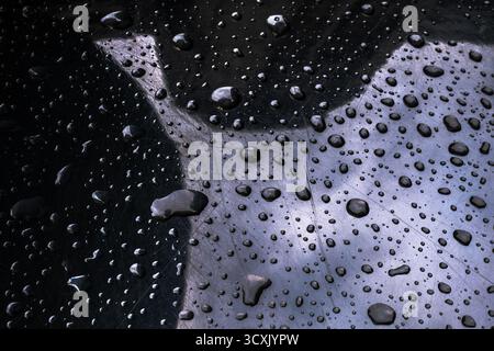 Heavily edited image of Droplets on scratched glossy black texture Stock Photo