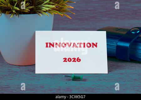 A card reads Innovation 2026, displayed with a plant in a white pot, next to a bundle of pens and a green push pin, symbolizing planning and future gr Stock Photo