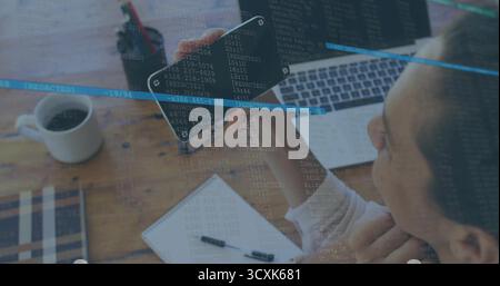 Developer examining code on smartphone by laptop on home office desk with code overlay, copy space Stock Photo