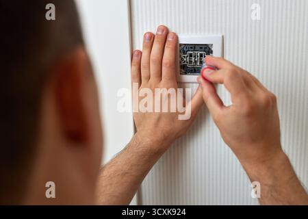 electrician working on light switch using screwdriver inside, close-up Stock Photo