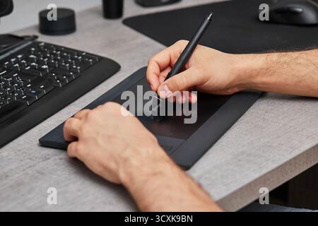 male hands drawing and retouching image on pc computer, using graphic digital tablet and stylus pen at office desk. Stock Photo