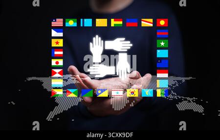 Concept of global teamwork and international partnership showing hands connected in unity above digital world map surrounded by flags, symbolizing col Stock Photo