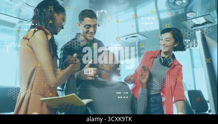 Collaborating tech team brainstorming with seated colleague in office using notebook and pen Stock Photo