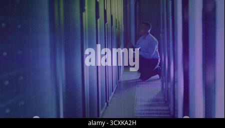 Kneeling African American technician inspecting server rack with LEDs in data center, with tablet Stock Photo