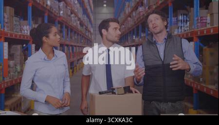 Labeling cardboard boxes at workstation, team in business attire in warehouse aisle using label gun Stock Photo